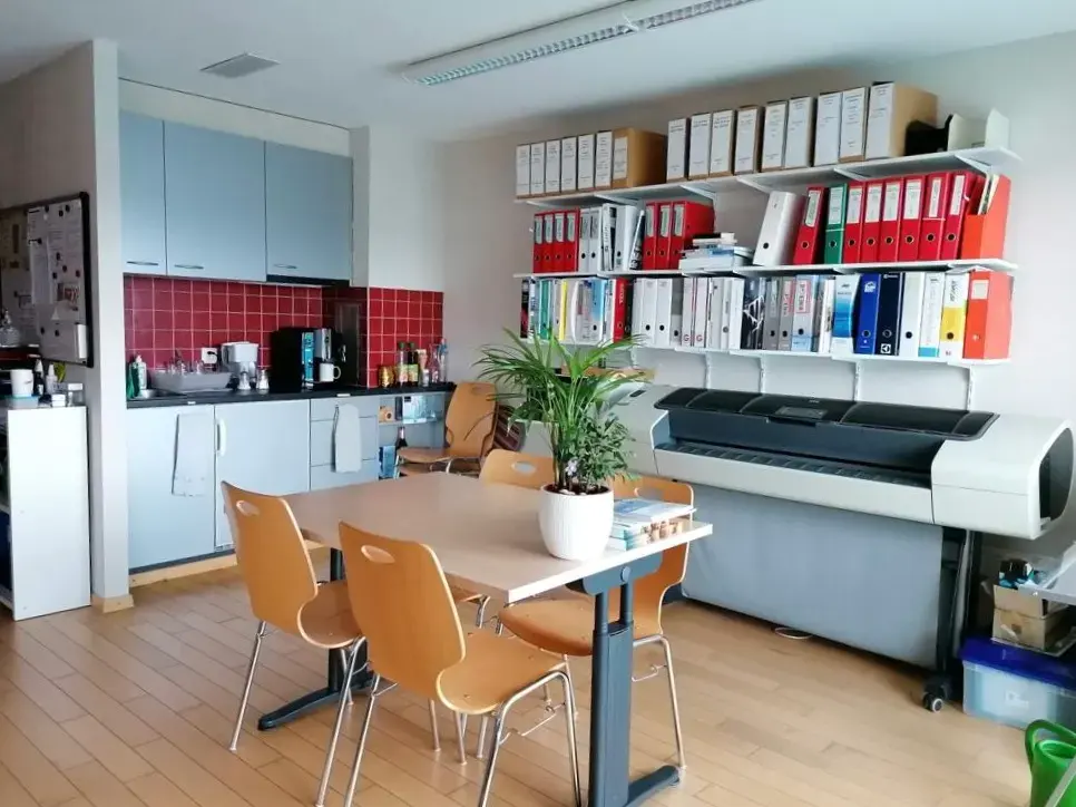 Ancienne cuisine de cafétéria et zone de pause du bureau, encombrée de dossiers, avant démolition.