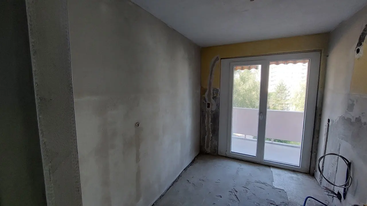 Étape de lissage des murs avant la mise en peinture d'un appartement à Fribourg.