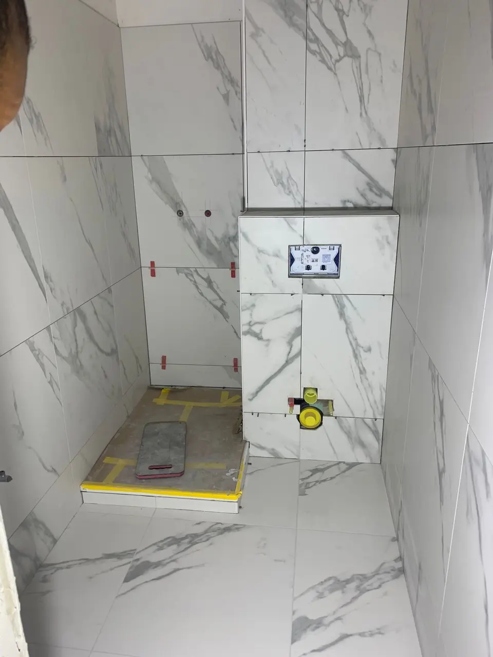 Pose de grands carreaux effet marbre dans la salle de bain en rénovation à Fribourg.