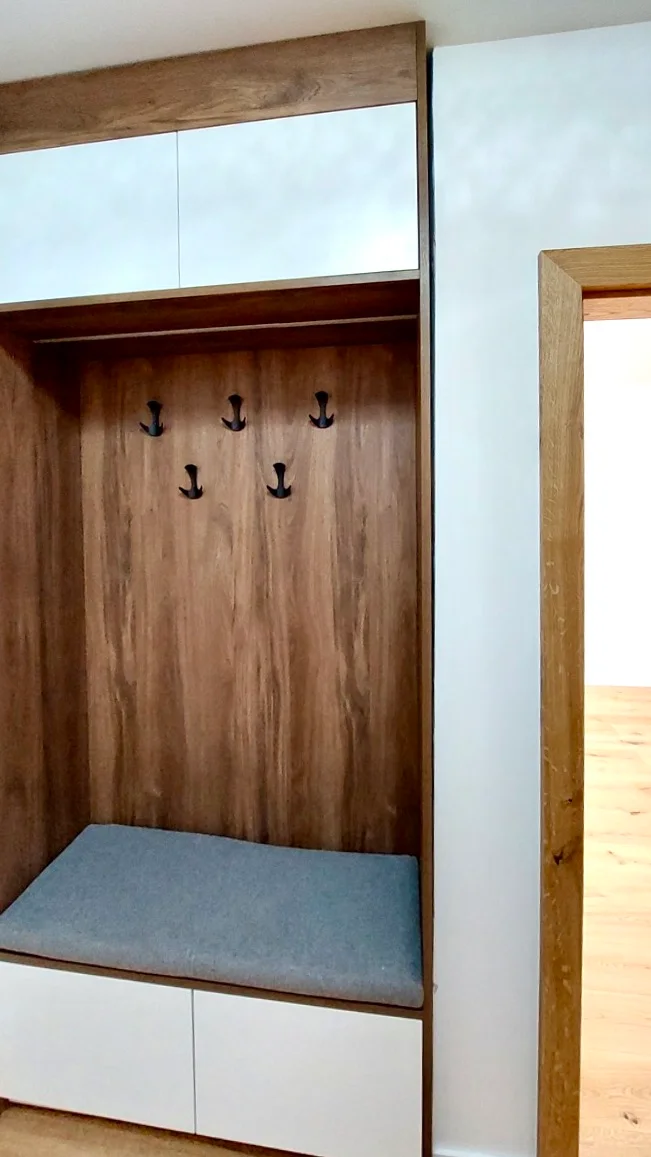 Dressing d'entrée en bois avec patères noires après rénovation à Fribourg.