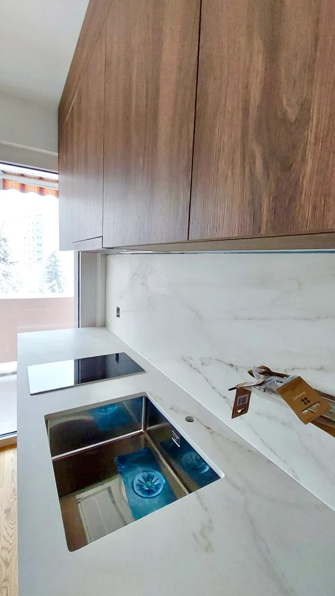 Cuisine contemporaine avec façades bois et crédence effet marbre à Fribourg.