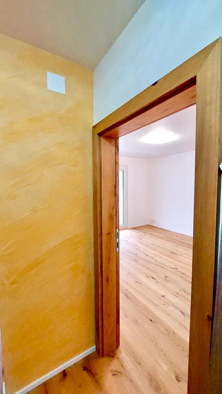 Couloir avec mur de couleur jaune et nouveau parquet en bois clair à Fribourg.