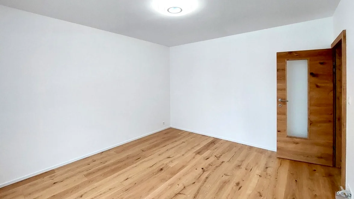 Grand séjour rénové avec murs blancs et parquet de qualité à Fribourg.